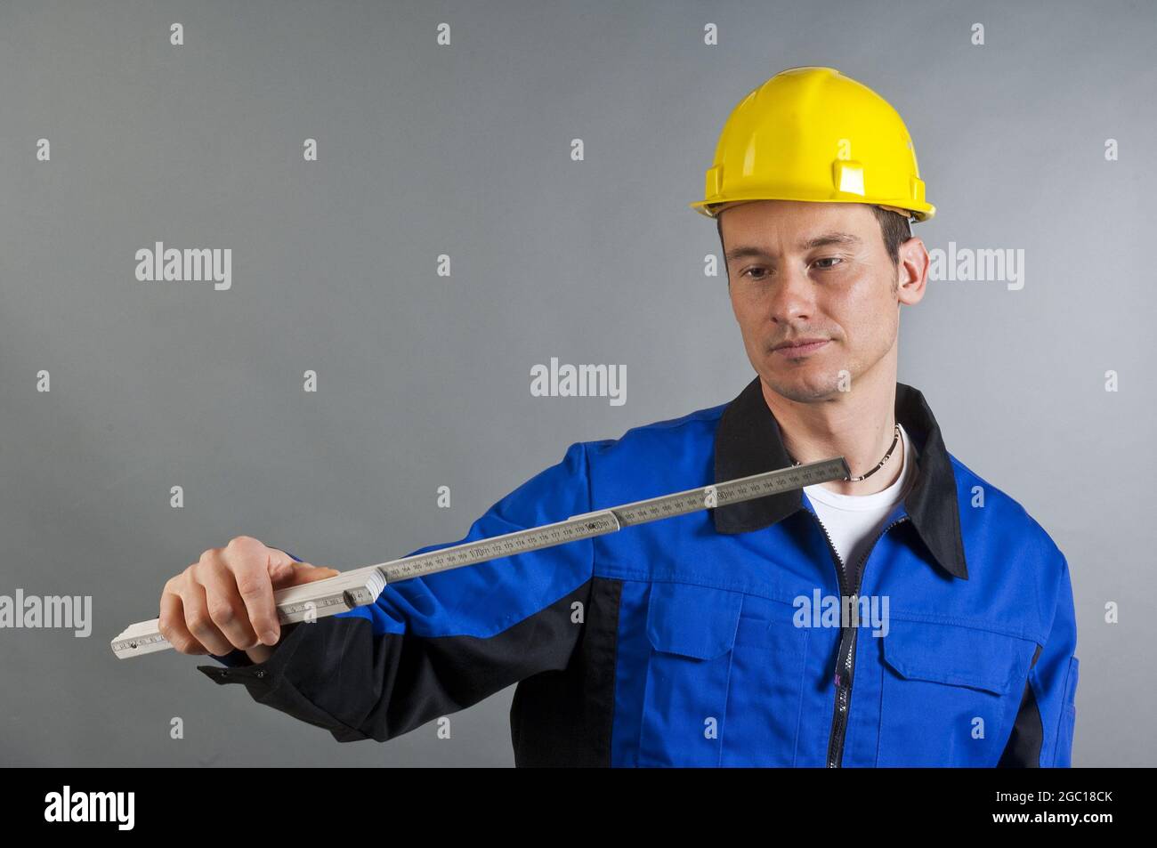 blue collar worker looking at a folding rule Stock Photo