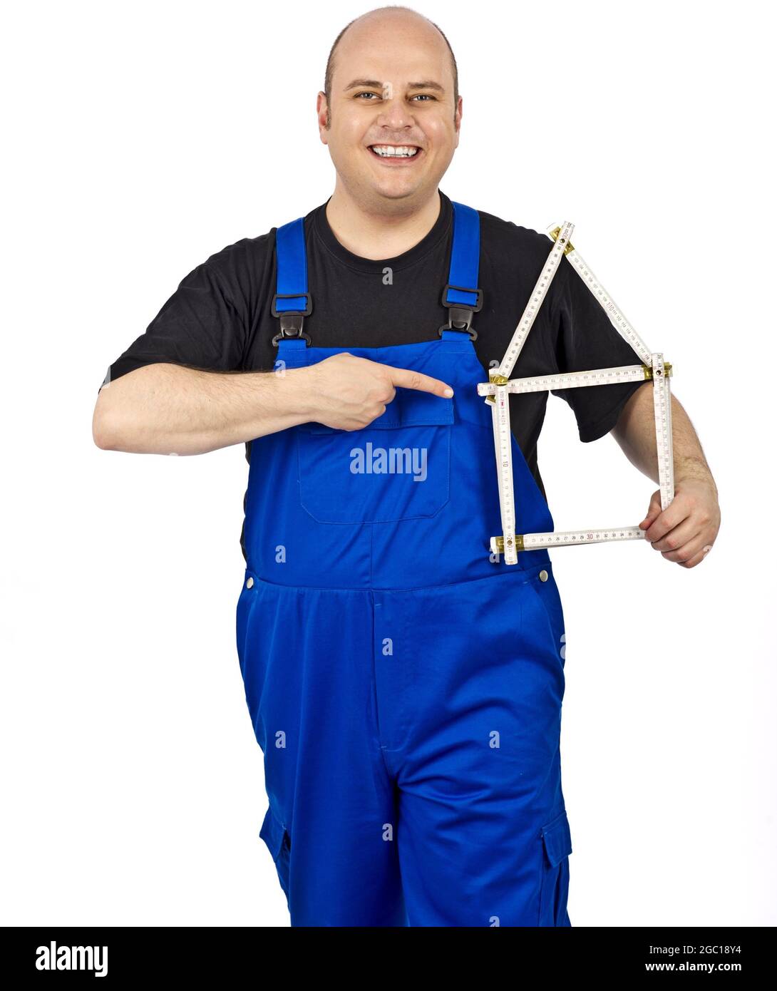 construction worker in blue dungarees pointing to a folding rule house Stock Photo