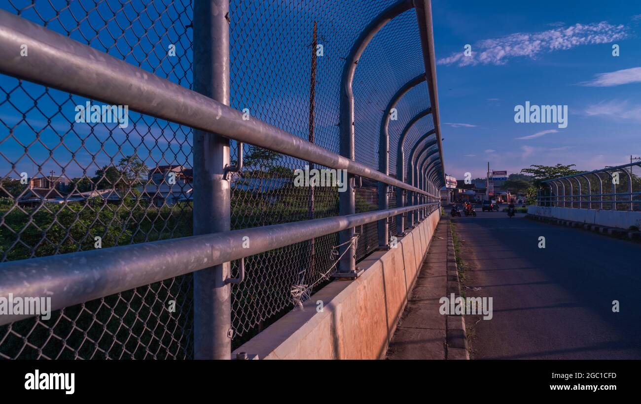 Bridge surrounded with metal fences under the cloudy blue sky in the city Stock Photo