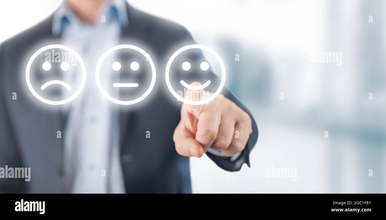 Rating concept. man choosing happy smile face emotion on blurry background. Businessman hand pointing the smiley face icon from screen as positive fee Stock Photo