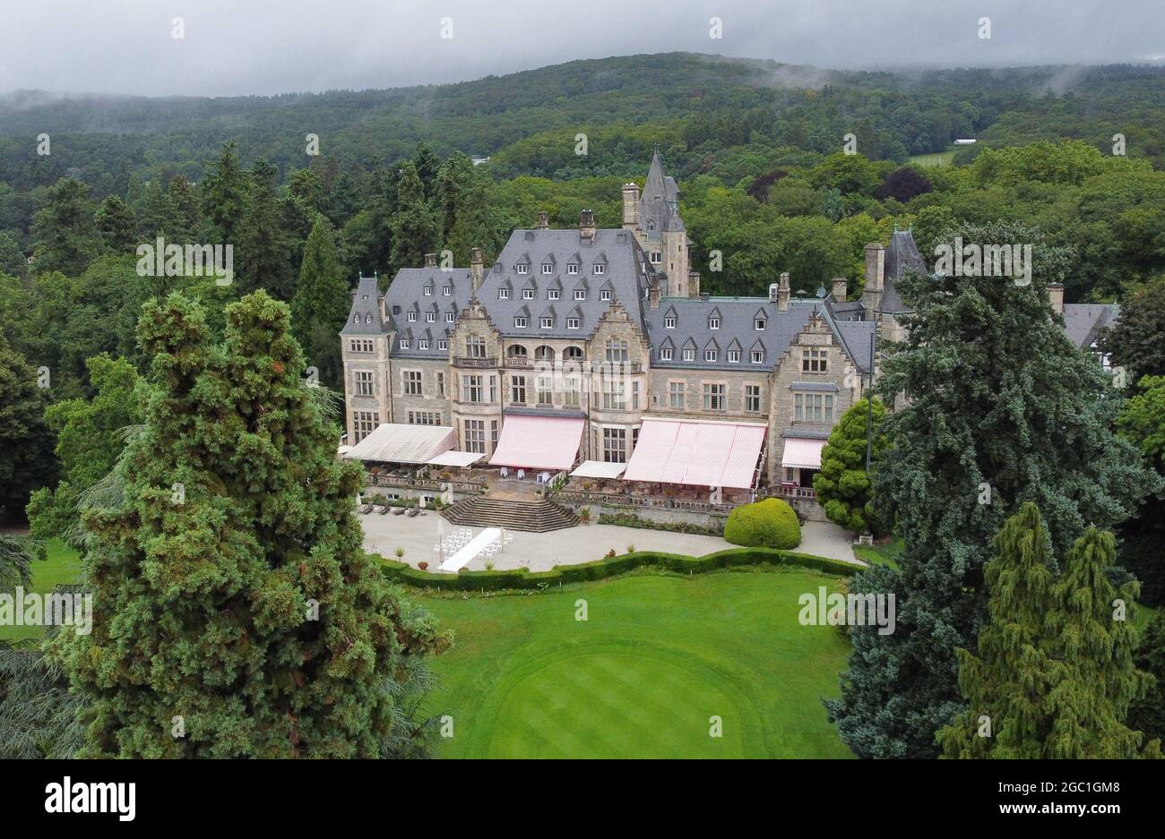 06 August 2021, Hessen, Kronberg: Surrounded by the park with golf course  and trees is the 5-star-superior Schlosshotel Kronberg (shot with drone).  Despite the Corona restrictions, a dozen feature films have been