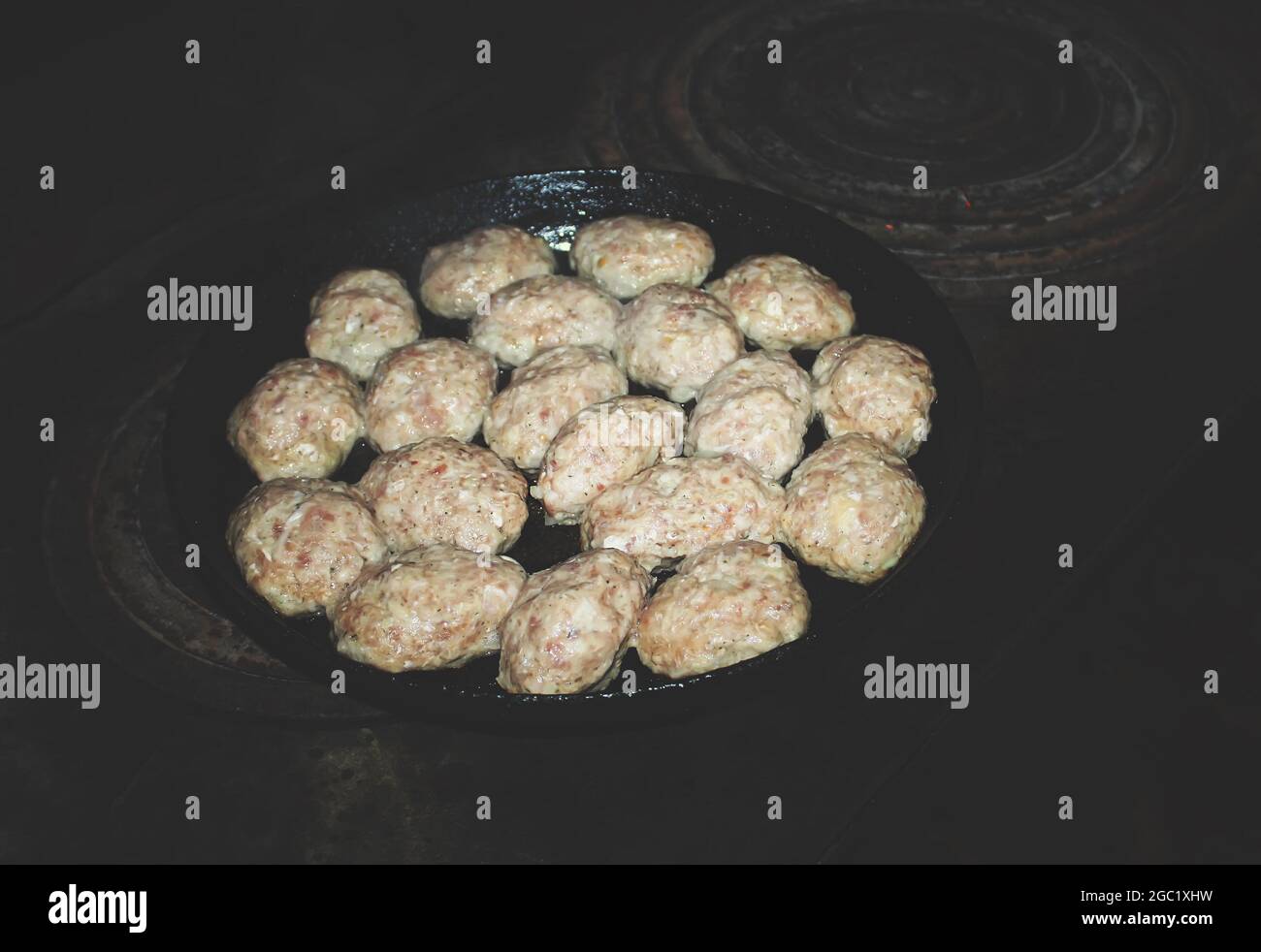 Crusted hamburger patties nin castiron skillet over flame Stock Photo