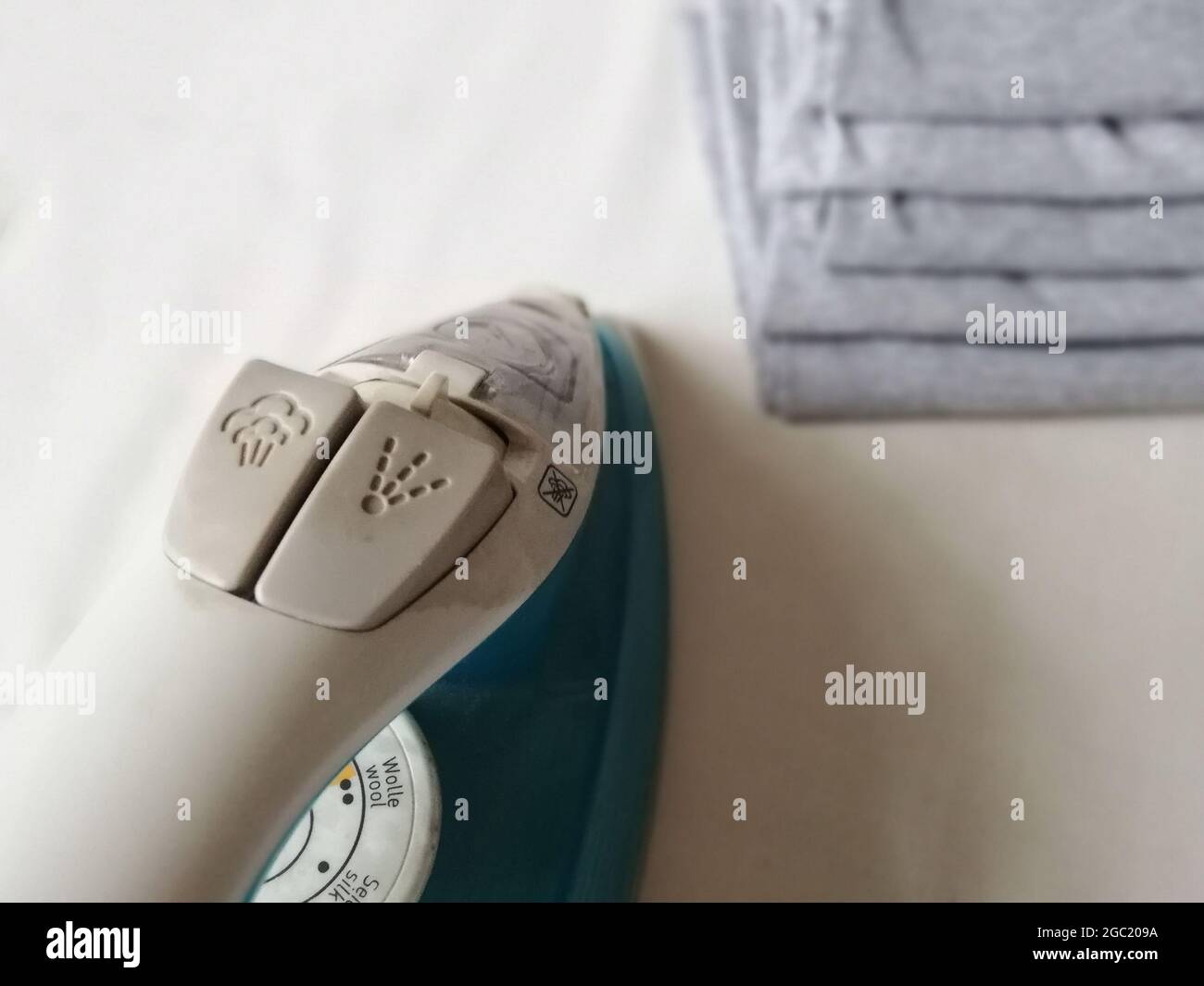 Shallow focus shot of iron and a pile of gray ironed clothes on the