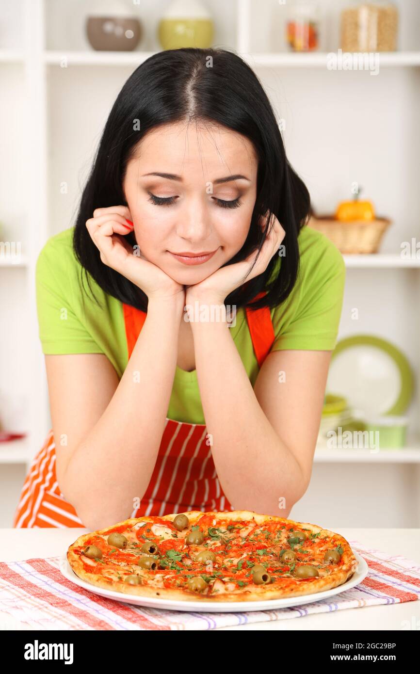 Girl housewife with delicious pizza on kitchen background Stock Photo