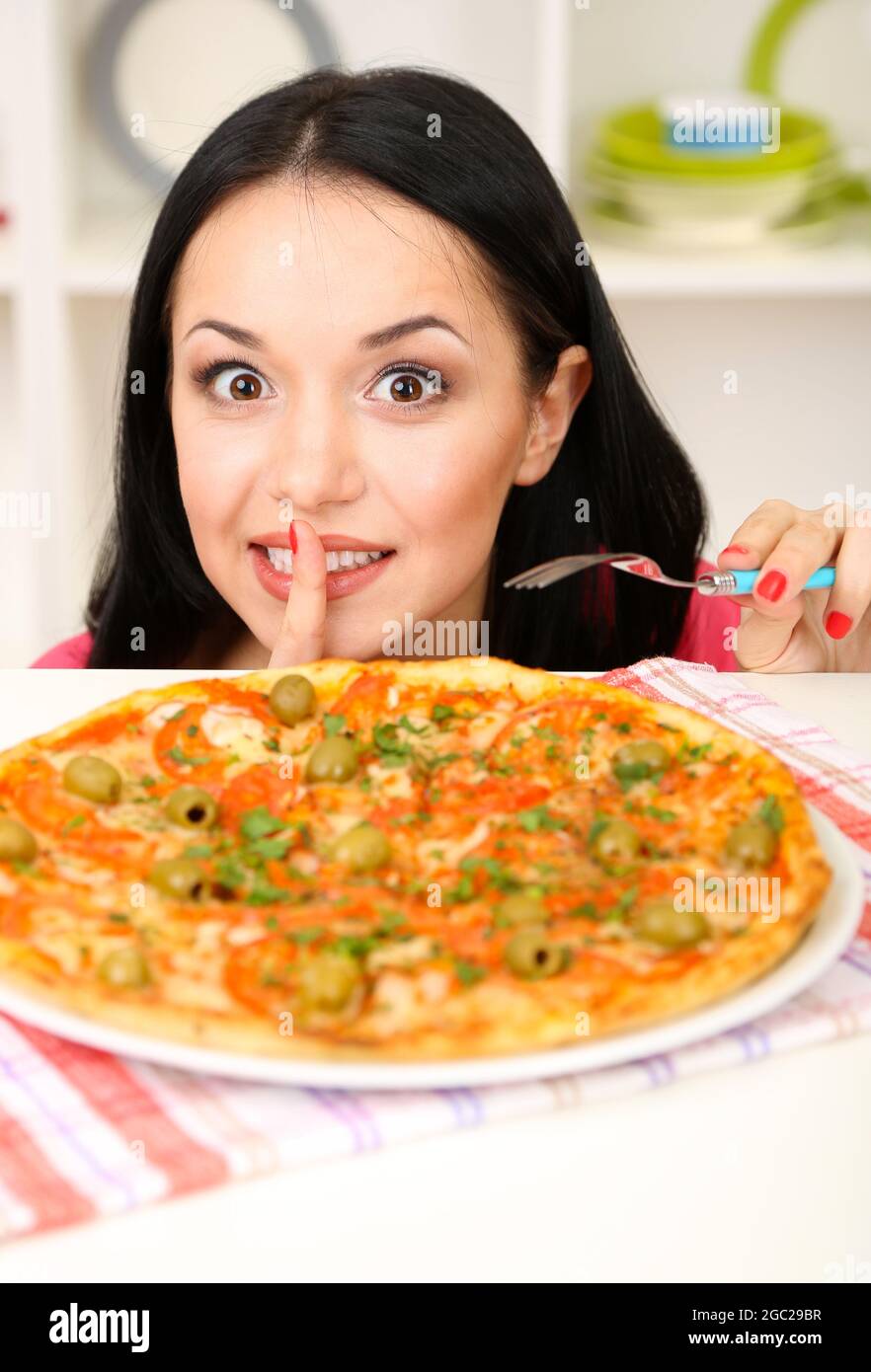 Beautiful girl wants to eat delicious pizza on kitchen background Stock Photo