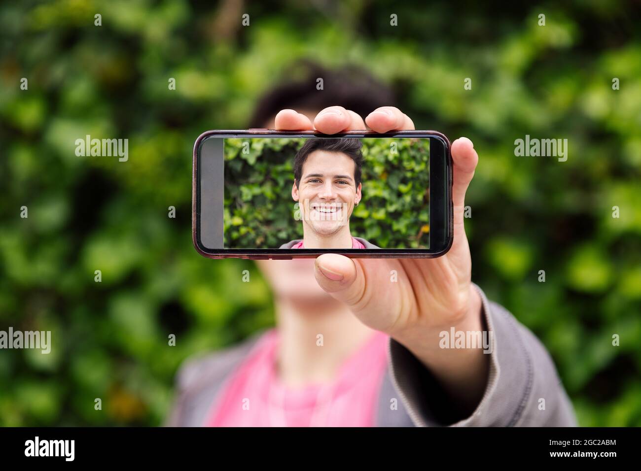 happy young man covering his face with a smart phone with a photo of ...