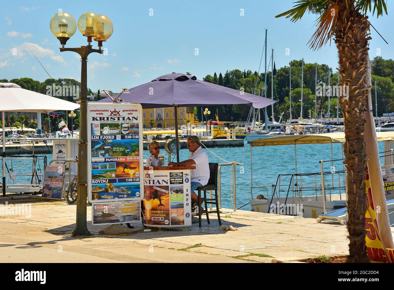 Porec, Croatia- July 10th 2021. A day trip vendor selling boat trips at the seafront waits for passing tourists in the historic medieval coastal town Stock Photo