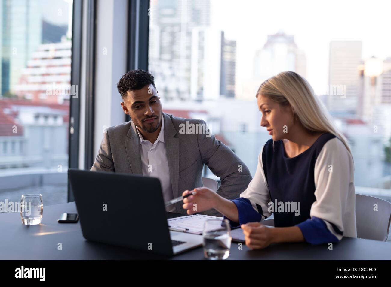 Two diverse male and female business colleagues talking and using ...