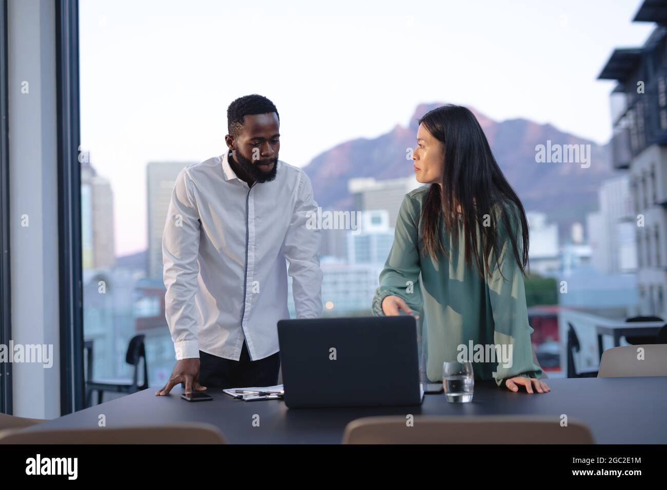Two diverse male and female business colleagues talking and using ...