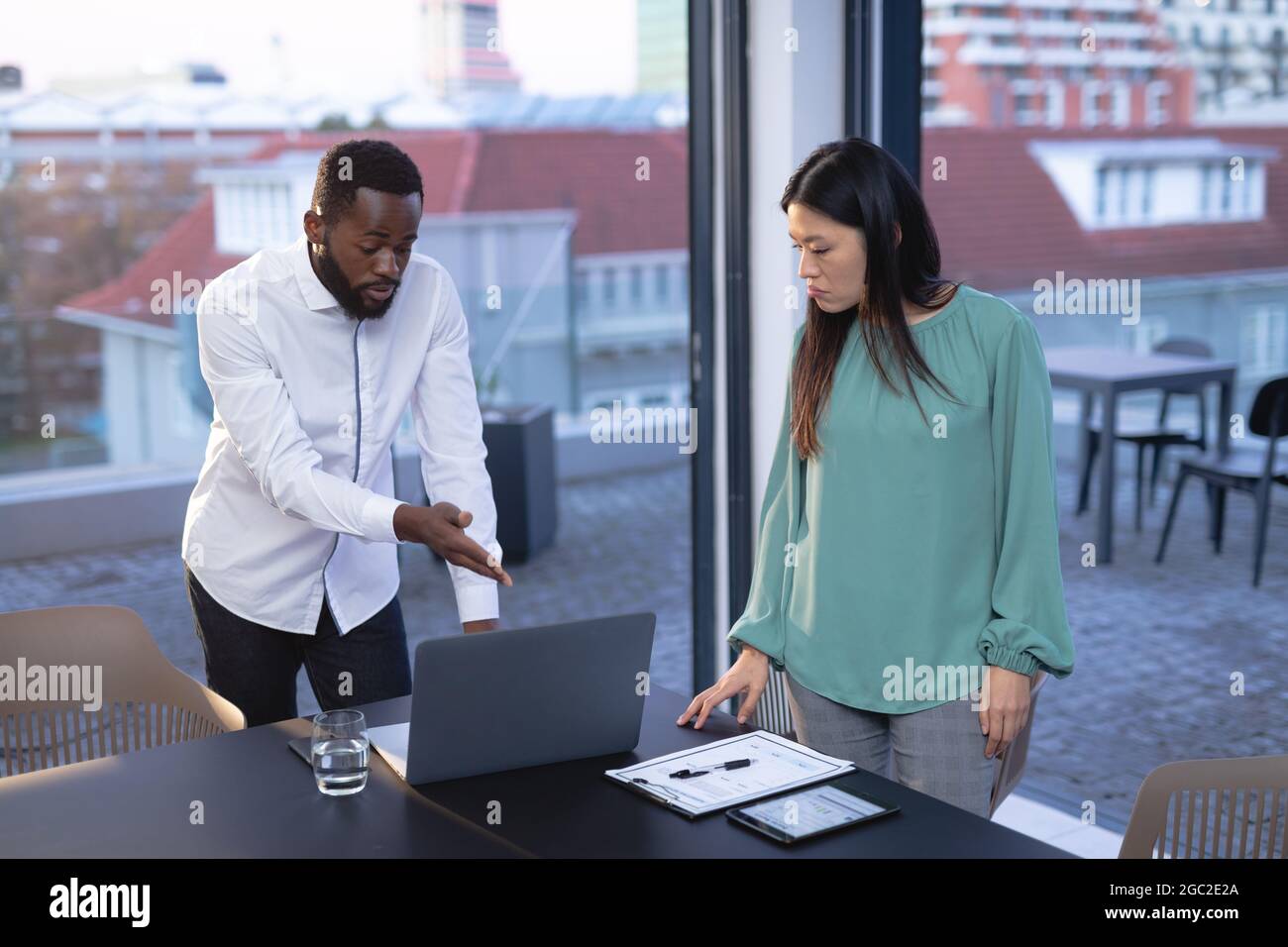 Two diverse male and female business colleagues talking and using ...