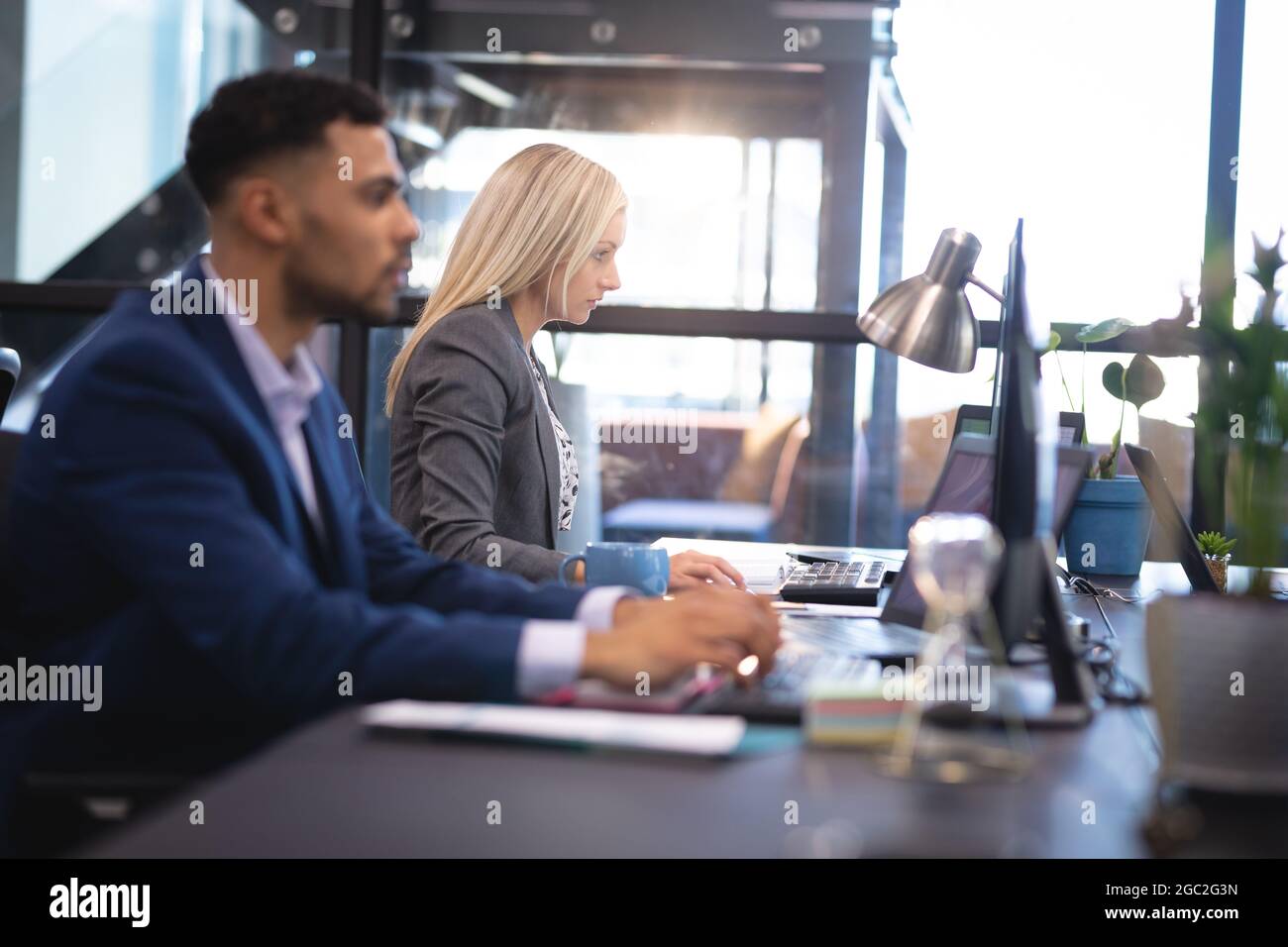 Diverse male and female business colleagues working together at desk ...