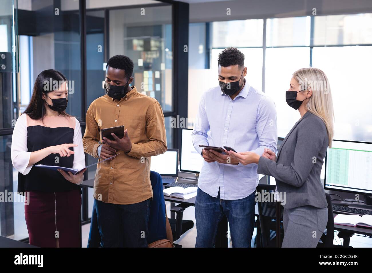 Diverse group of business colleagues wearing face masks and having ...