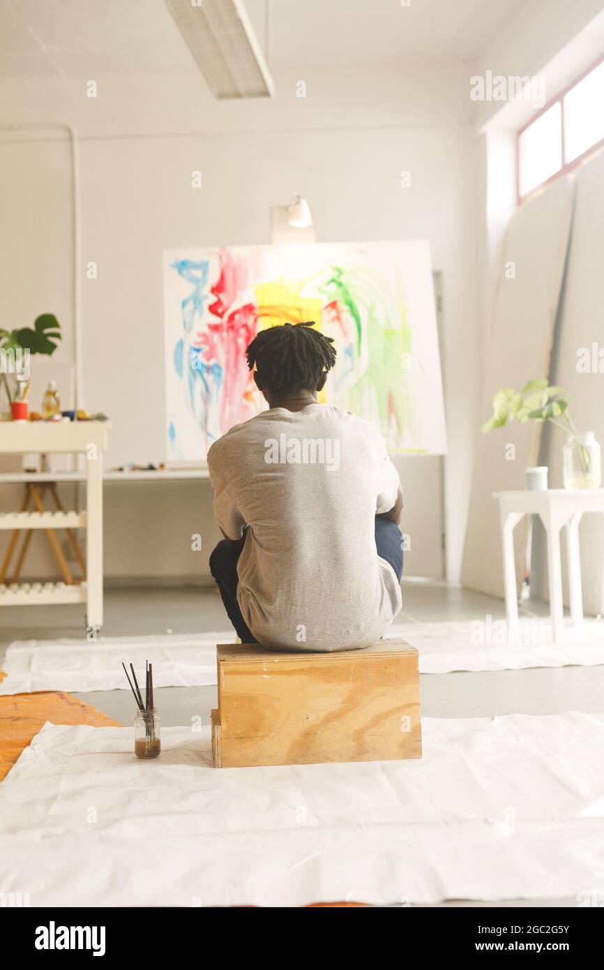 African american male painter at work looking at artwork in art studio Stock Photo