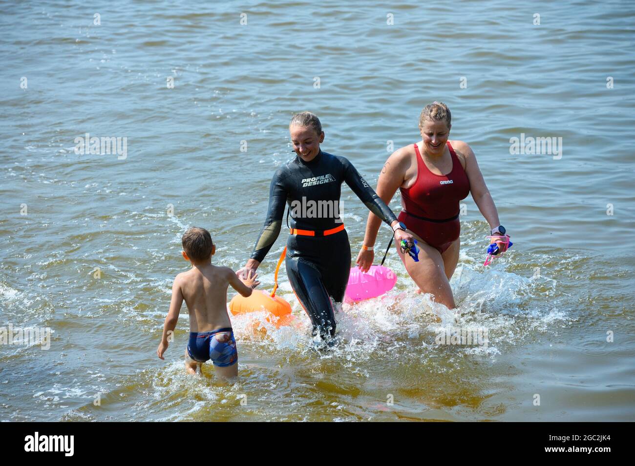 Two women swimmers in swimsuits going out of water of the river after