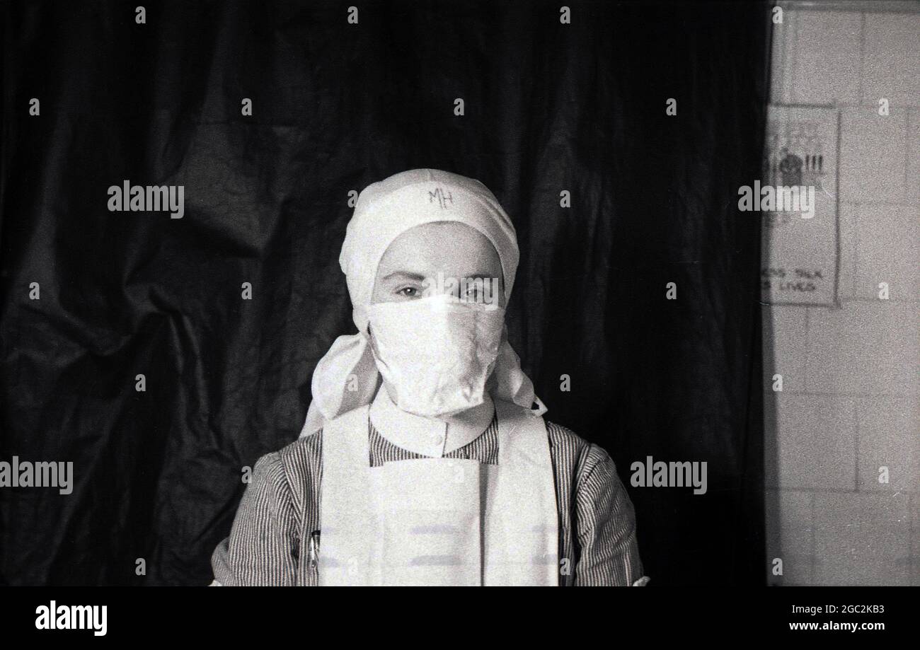 1950s, historical, sitting infront of a black screen, a uniformed nurse wearing a headscarf and a facemask, England, UK. Stock Photo