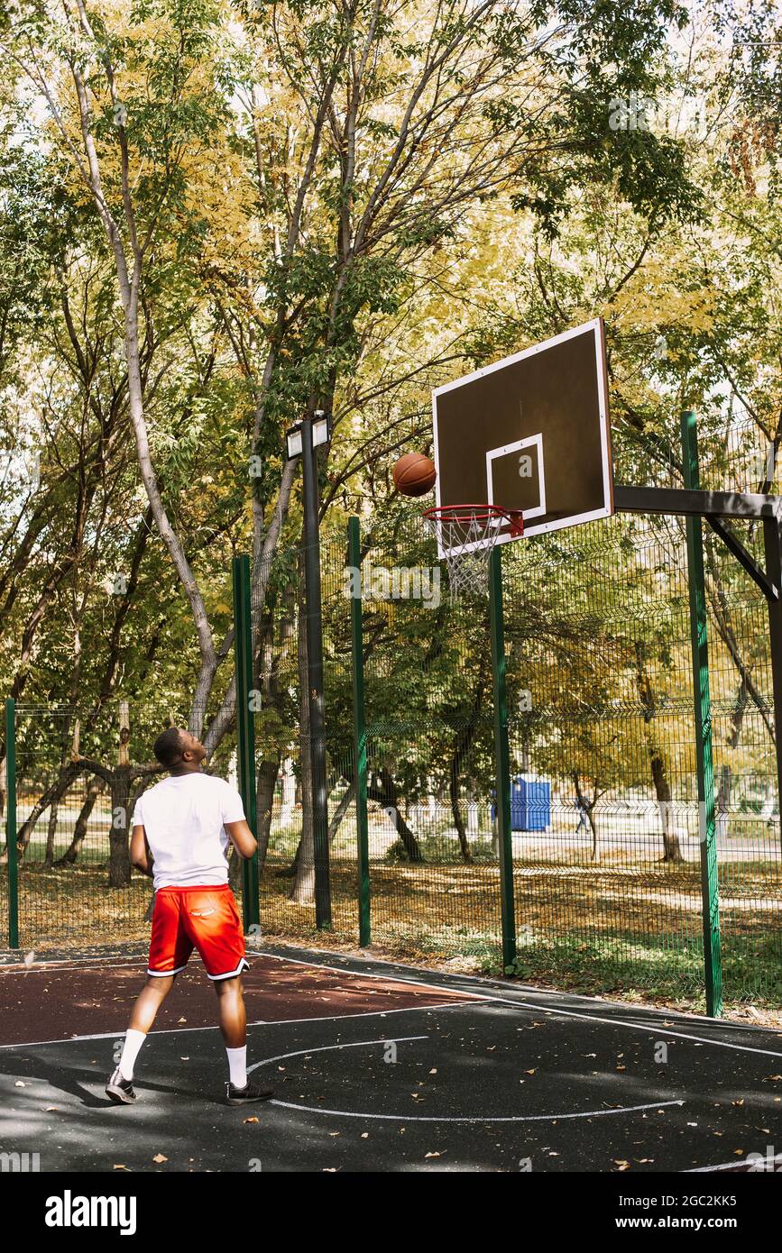 Basketball player hangs on the rim.attractive,laugh,sport games,street  ball,black,sport outfit,casual wear,black clothes Stock Photo