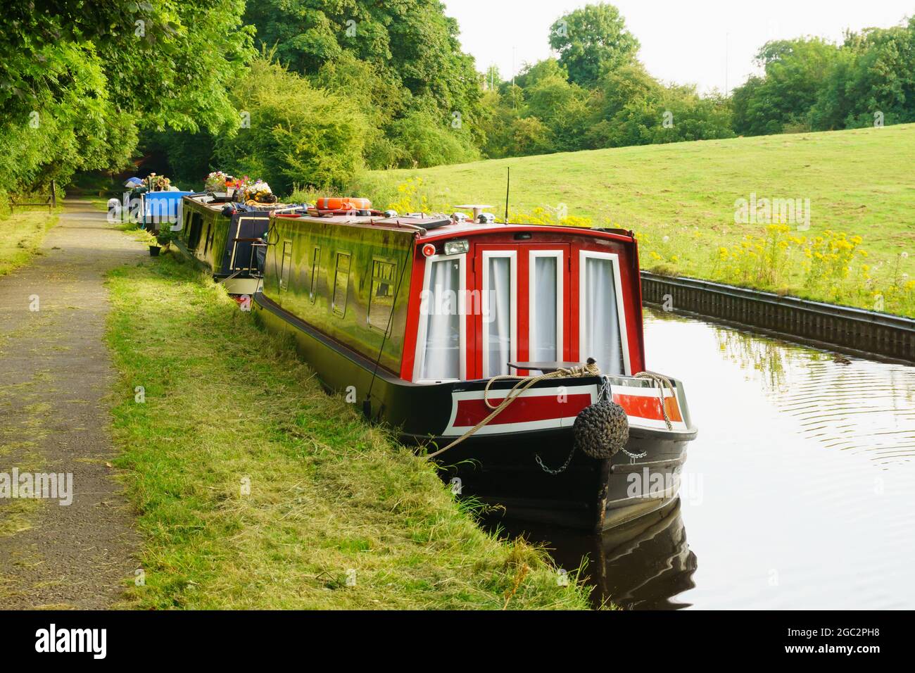 Narrowboats or barges moored on the Llangollen canal on a summer evening outside the Welsh village of Chirk in North Wales Stock Photo