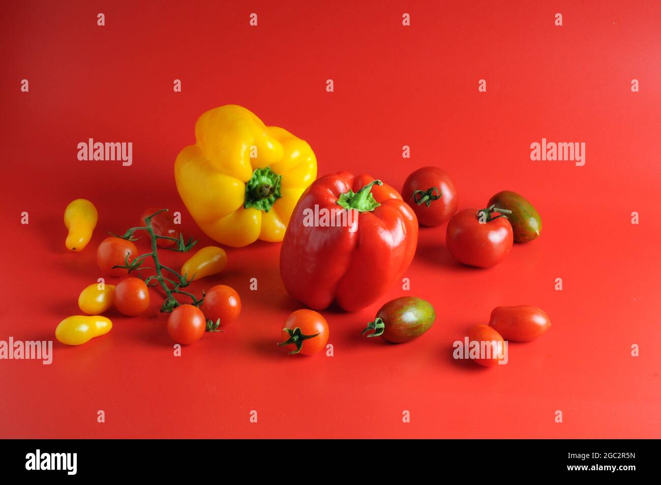 Fresh ripe tomatoes and Peppers on red background Stock Photo