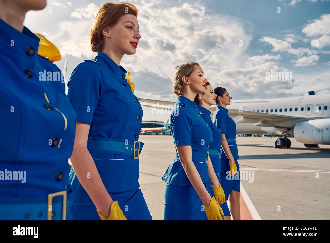 Group of pretty air hostesses crossing the airfield Stock Photo