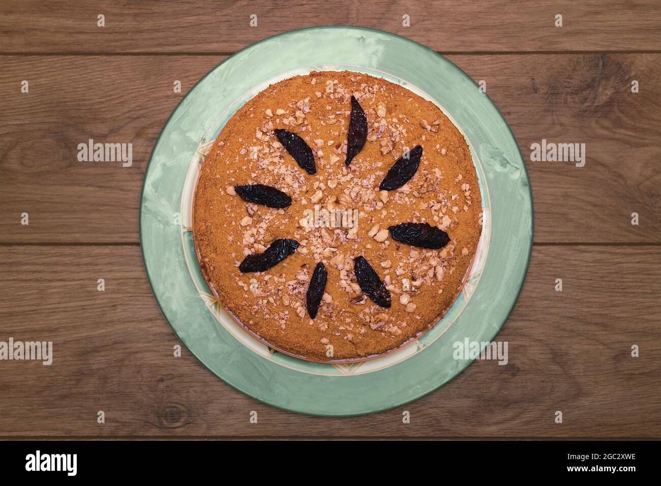 Homemade honey cake with cream, nuts and prunes on a wooden table. Top view Stock Photo