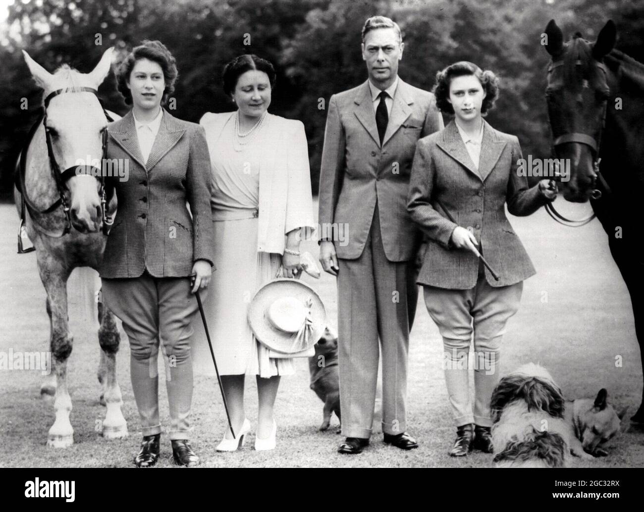 Her Majesty, Queen Elizabeth, The Queen Mother with King George VI and their daughters Princess Elizabeth and Princess Margaret. Pictured with their favourite dogs and horses at the Royal Lodge, Windsor. Grey horse is Colleen, Black Horse is Shannon, Foreground Tibetan Lionhound called Ching and their two Corgi Little Welsh Hounds, Susan and Crackers. September 1946 Stock Photo