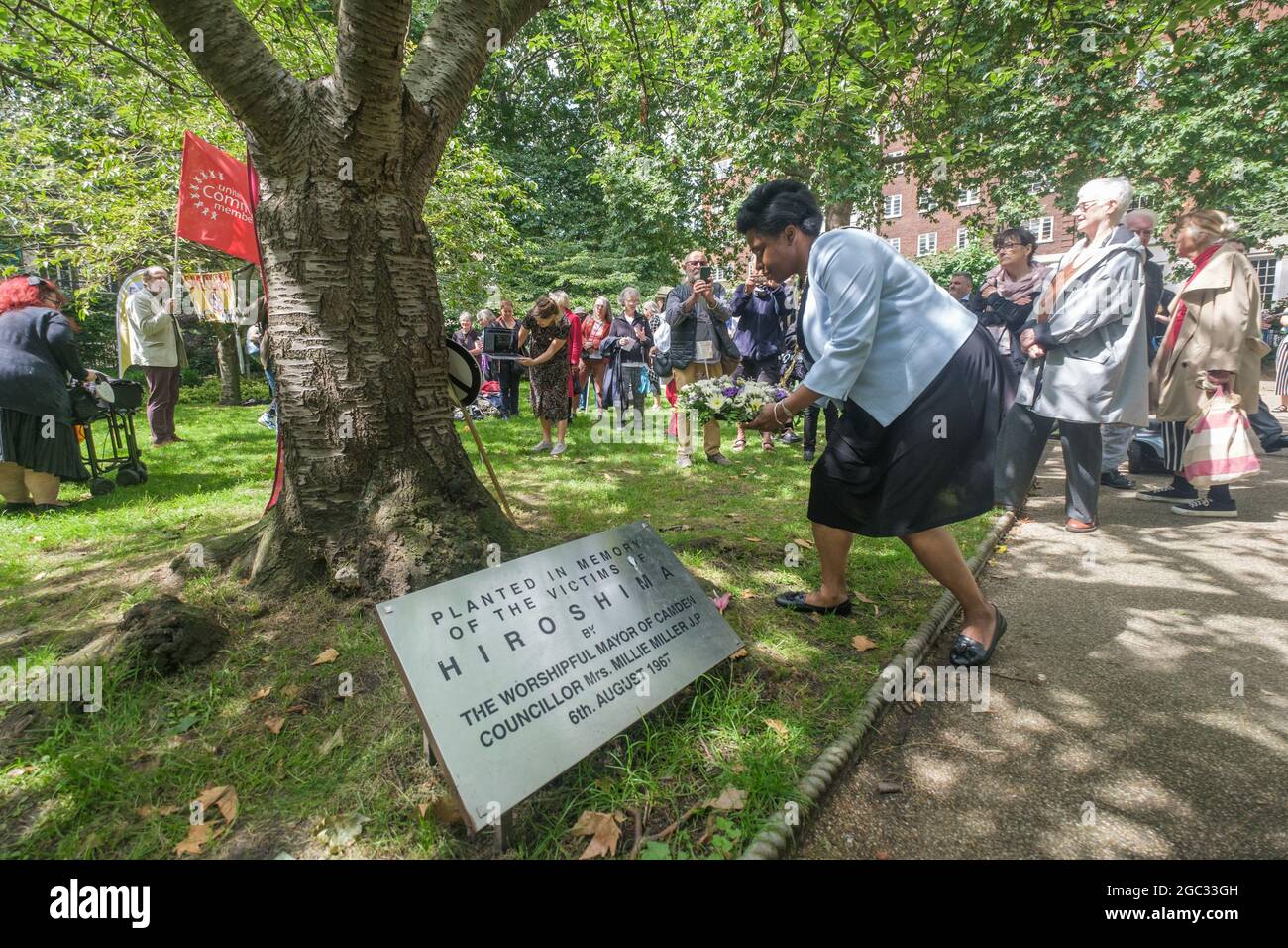 London, UK. 6th August 2021. Sabrina Francis, Mayor of Camden lays a wreath at the Hiroshima Cherry Tree. 76 years after atomic bombs were dropped on Hiroshima and Nagaski, London CND met in Tavistock Square to remember the many killed and survivors who are still suffering the event, and to celebrate the UN treaty prohibiting nuclear weapons which came into force this January. They called on the government to end the UK's nuclear weapon programme. Peter Marshall/Alamy Live News Stock Photo