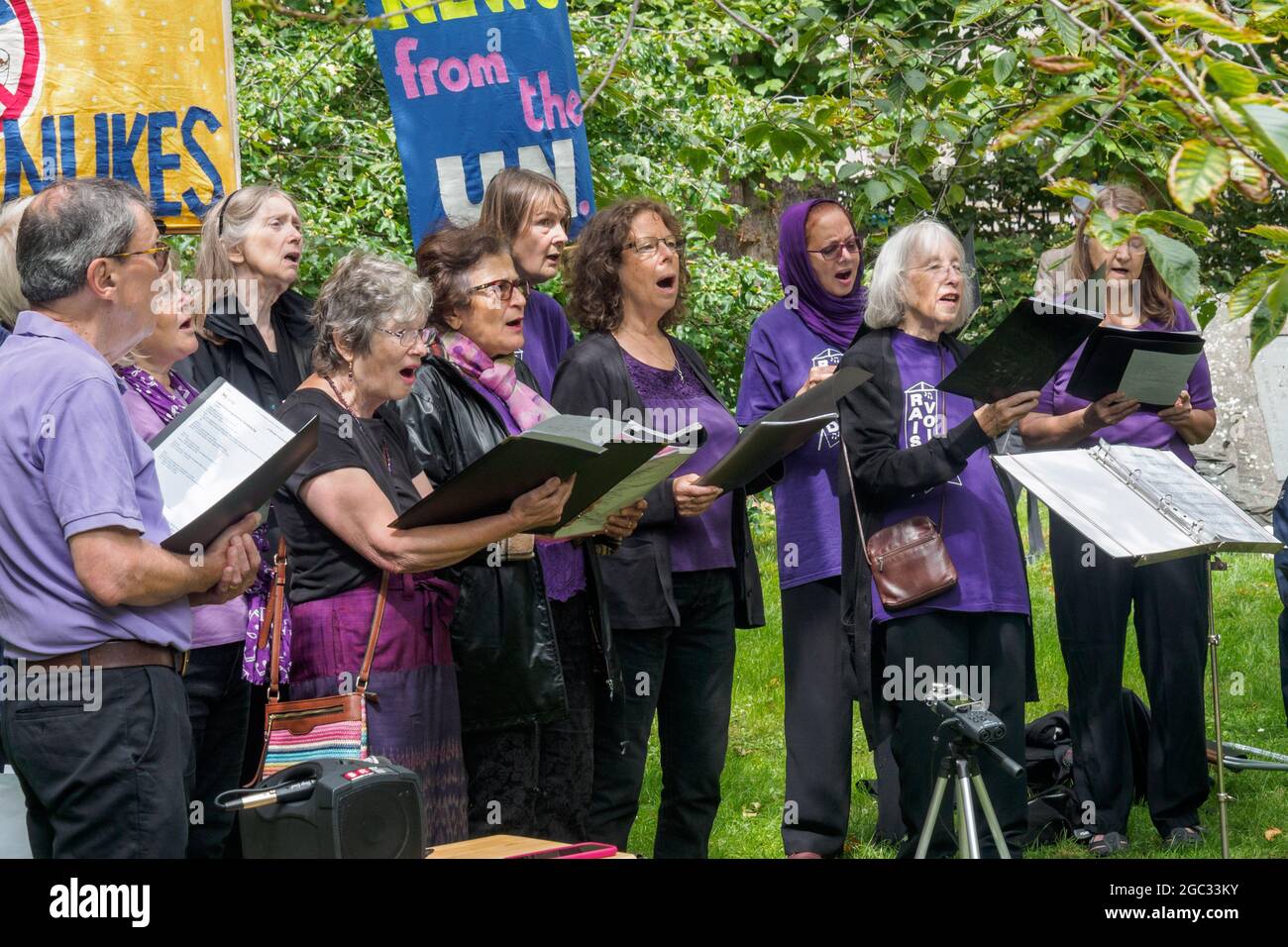 London, UK. 6th August 2021. Raised Voices sing a Japanese song about atomic weapons. 76 years after atomic bombs were dropped on Hiroshima and Nagaski, London CND met at the Hiroshima Cherry tree in Tavistock Square to remember the many killed and survivors who are still suffering the event, and to celebrate the UN treaty prohibiting nuclear weapons which came into force this January. They called on the government to end the UK's nuclear weapon programme. Peter Marshall/Alamy Live News Stock Photo