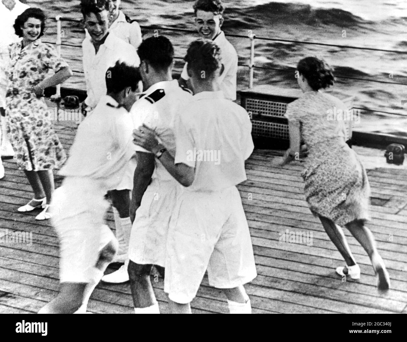 Princess Elizabeth celebrates her 21st birthday with a deck game with Princess Margaret and crew of the HMS Vanguard during a voyage to South Africa. She is pictured laughing at he sister who is being chased by an officer.. 21st April 1947 Stock Photo