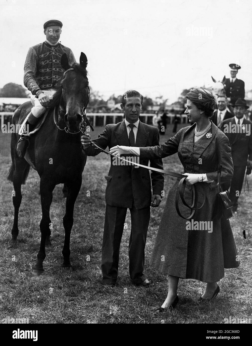 HM Queen Elizabeth II leads her horse Carrozza in after it has won the 179th Oaks Stakes, with Lester Piggott in the saddle. In a photo-finish, Silken Gilder, ridden by J Eddery, was given second, and Rose Royal II, the favourite with J Massard in the saddle, third. 7th June 1957 Stock Photo