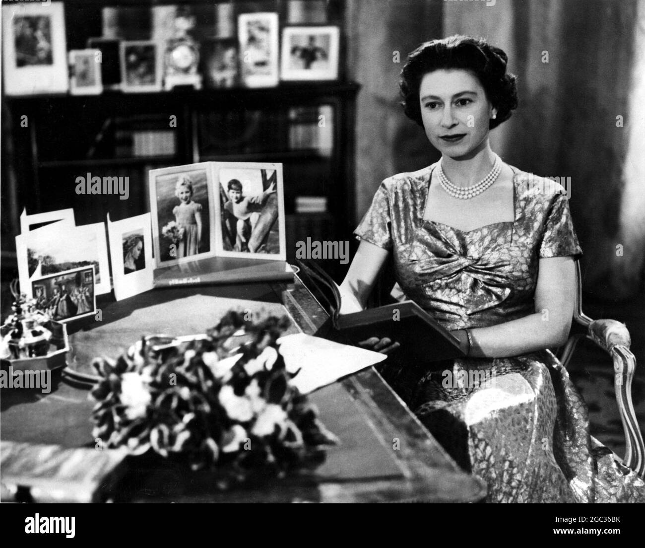 HM The Queen makes her Christmas broadcast. When HM The Queen made her Christmas broadcast from the long library of Sandringham, Norfolk. it was the first occasion on which this traditional message was televised, and was also the 25th anniversary of King George V's first radio message to the Commonwealth. Picture shows MH The Queen shortly after the telecast with 'Pilgrims Progress' from which she quoted a passage. 25th December 1957 Stock Photo