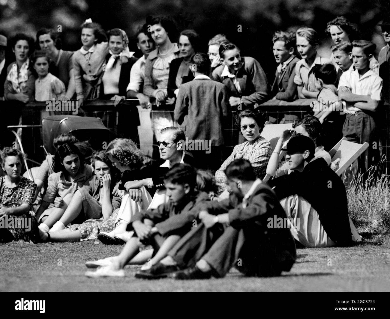 Royal Spectators Watch Village Cricket Match Seated among the spectators at the village cricket field at Mersham-le-Hatch, near Ashford, Kent, are the Duke of Edinburgh (on ground wearing sun-glasses), Princess Elizabeth (in deck chair beside him), Lady Brabourne (right, in deck chair) and Lord Brabourne (on ground beside her). The Duke was waiting to bat for Mersham in a match against the neighbouring village of Aldington. He was out l.b.w. to the first ball he received, but he took three of the Aldington wickets for 27 runs. The Duke's team won by 38 runs. The Duke and Princess Elizabeth wer Stock Photo