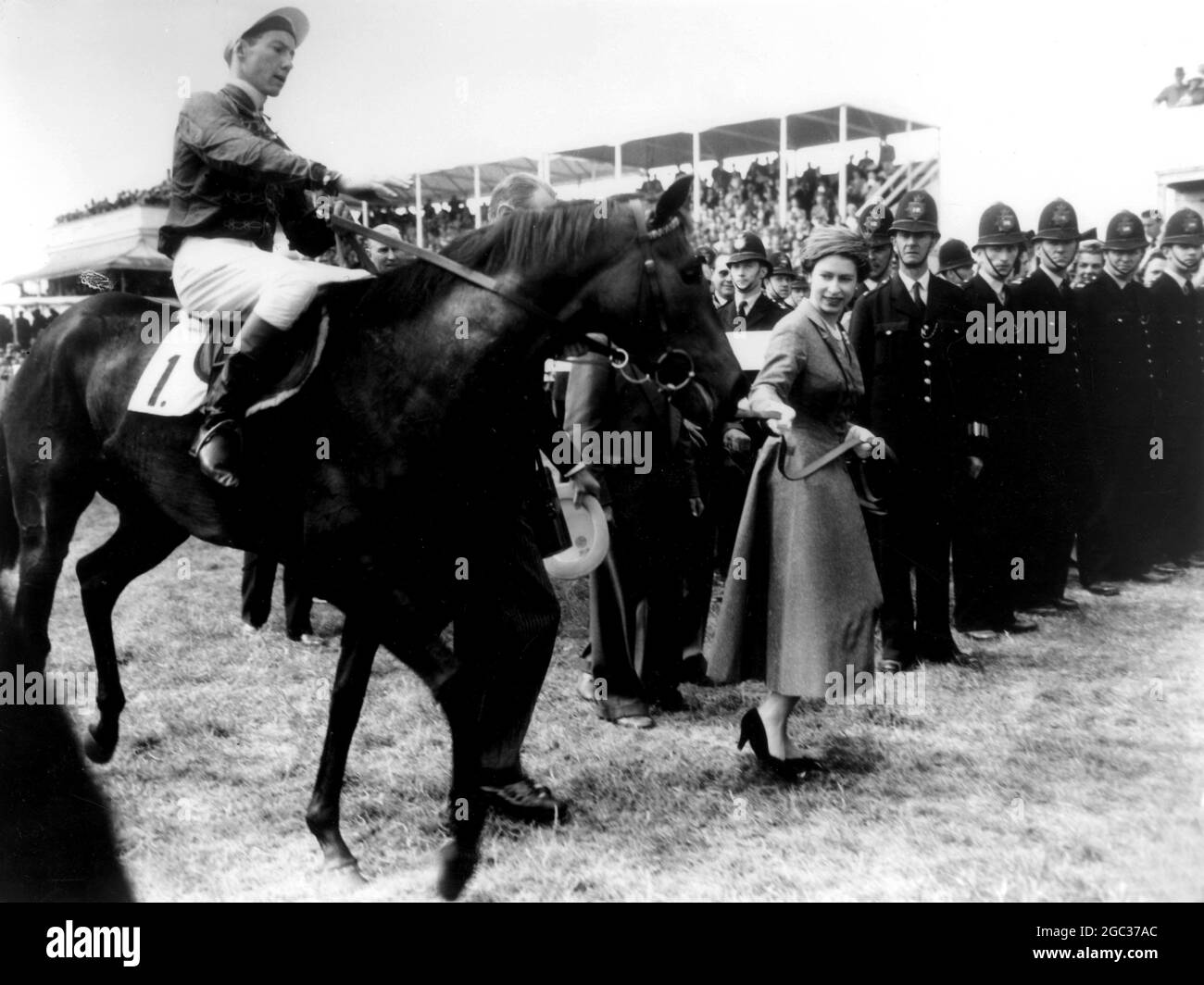 HM Queen Elizabeth II leads her horse Carrozza in after it has won the 179th Oaks Stakes, with Lester Piggott in the saddle. 7th June 1957 Stock Photo