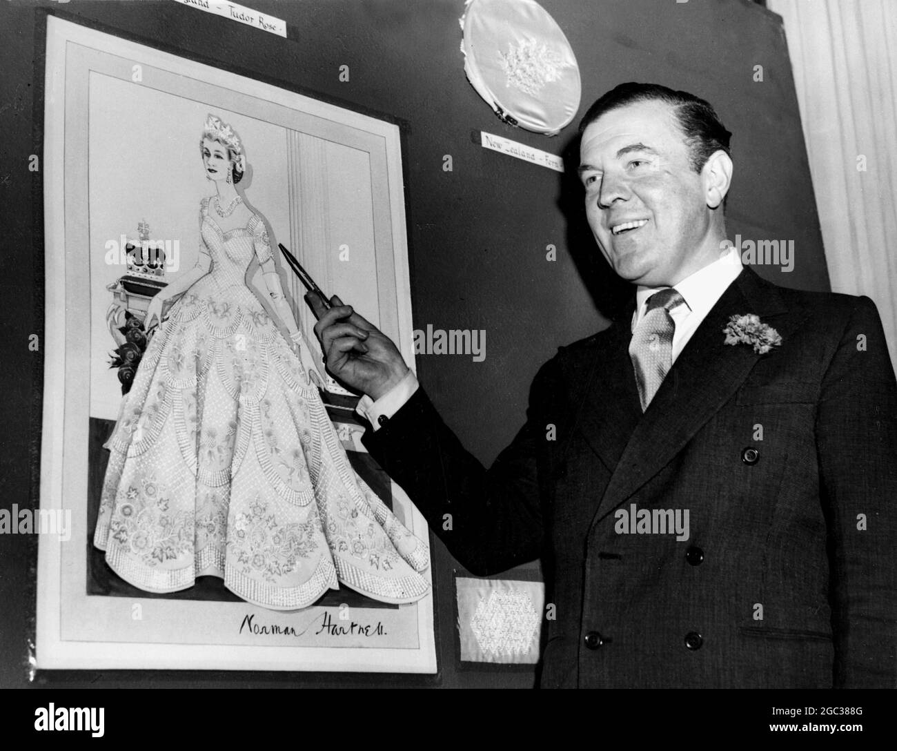 Norman Hartnell seen with his sketch of the Queen's gown to be worn for the coronation, which is in white satin embroidered with the emblem of Britain and the Commonwealth. June 1953 Stock Photo