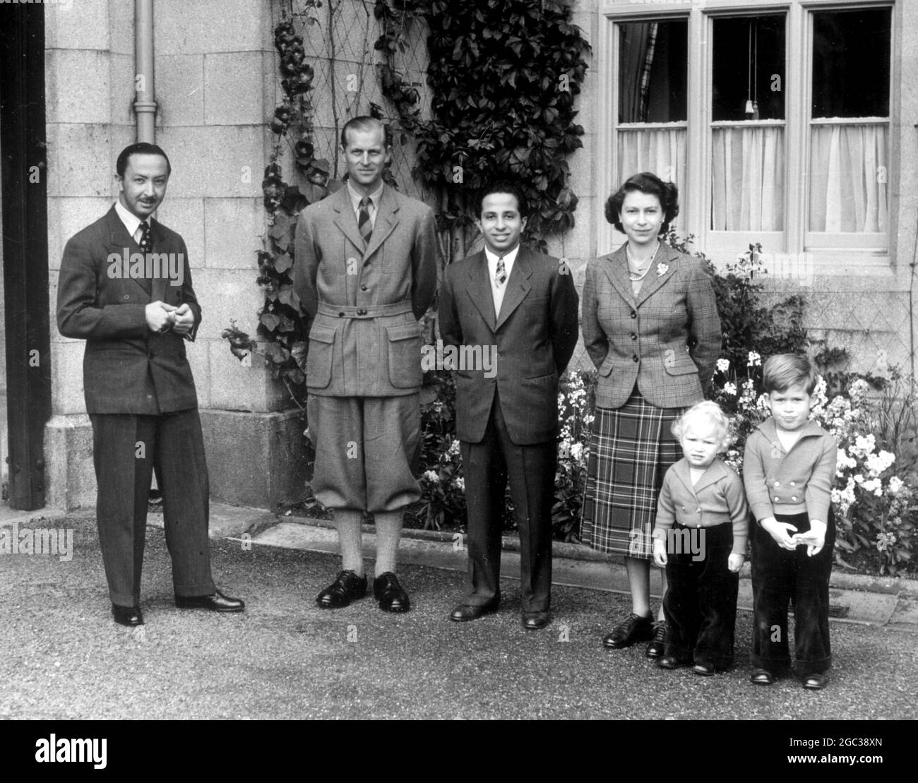 Balmoral, Scotland: The Duke of Edinburgh stands between Princess Ann and Prince Charles, as, together with Queen Elizabeth, they pose for their picture in the grounds of Balmoral Castle with 17-year old King Feisal of Iraq and his uncle, Emir Abdul Illah, the Prince Regent. The boy-King, an ex-Harrow schoolboy, is the guest of the Queen and Duke at Balmoral, their country home in Scotland. 26 September 1952 Stock Photo
