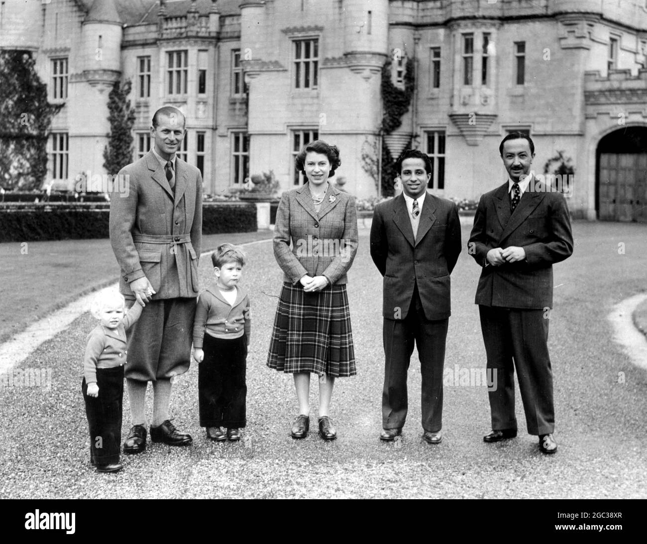 Balmoral, Scotland: The Duke of Edinburgh stands between Princess Ann and Prince Charles, as, together with Queen Elizabeth, they pose for their picture in the grounds of Balmoral Castle with 17-year old King Feisal of Iraq and his uncle, Emir Abdul Illah, the Prince Regent. The boy-King, an ex-Harrow schoolboy, is the guest of the Queen and Duke at Balmoral, their country home in Scotland. 26 September 1952 Stock Photo