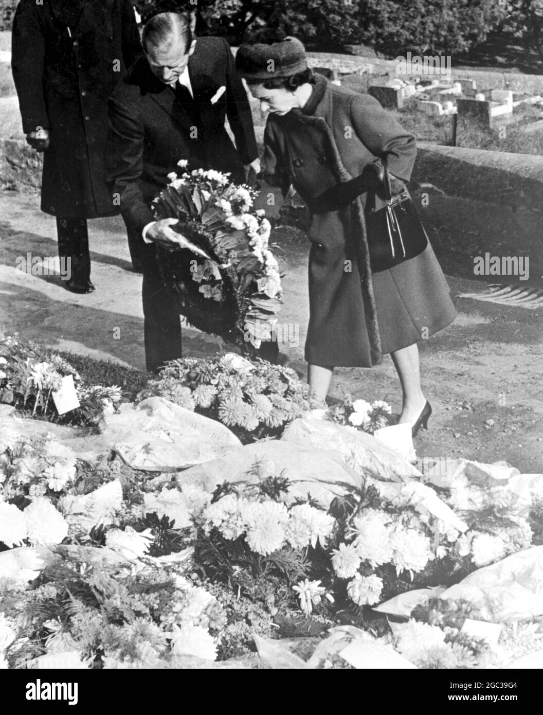 Aberfan, Wales: Britian's Queen Elizabeth II and her husband Prince Philip, Duke of Edinburgh lay a wreath upon the grave where 81 children and 1 adult were buried on Thursday; When the royal couple visited this disaster village today, October 29. Nearly 150 persons are known to have died in the coal tip slip which hit Aberfan in general and Pantglas School in particular eight days ago. 29 October 1966 Stock Photo