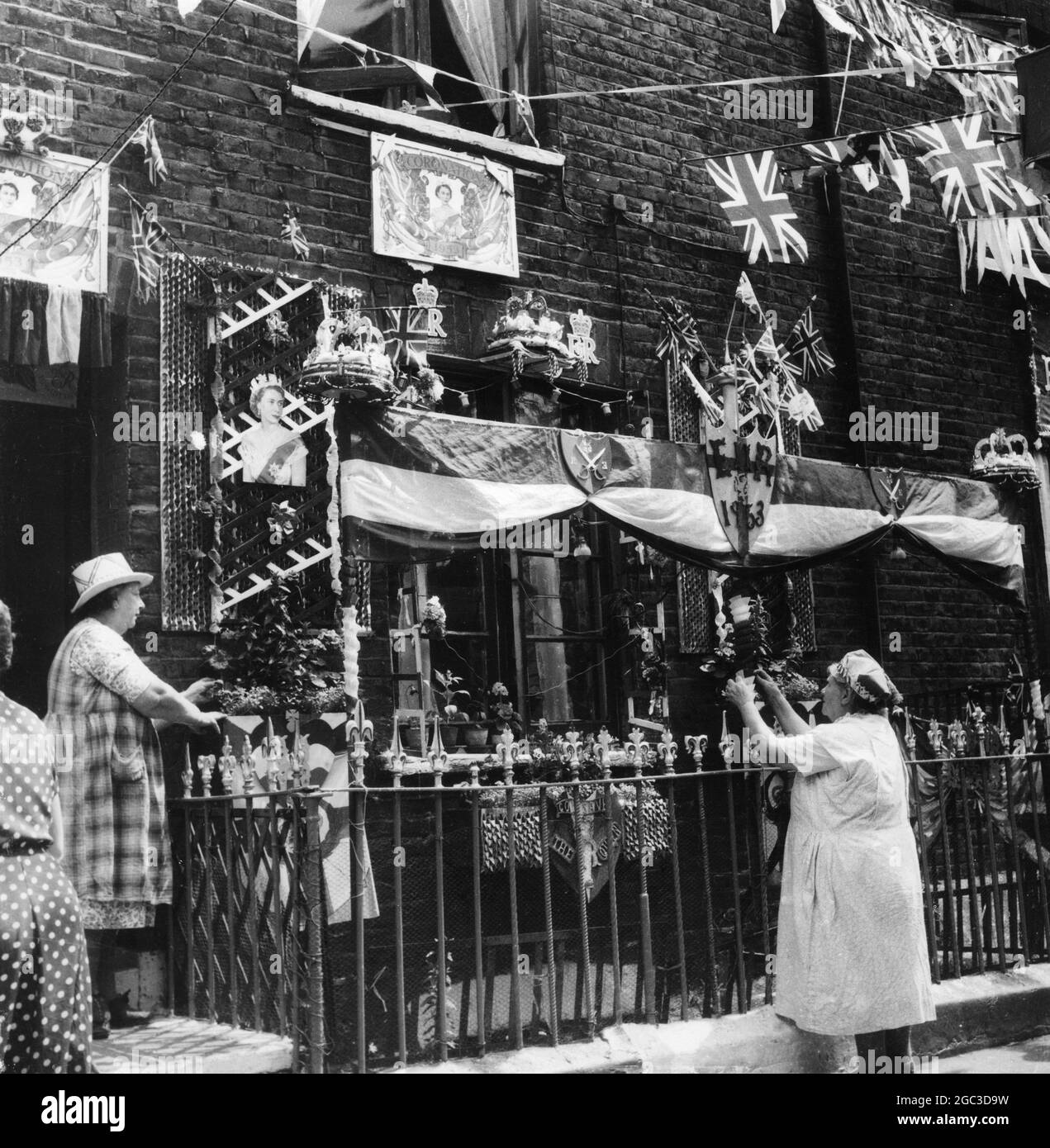 Landlady Mrs Jane Rudd (right) and her lodger Mrs L Cooling (left) put finishing touches to the Coronation decorations on their house in Godson Street Finsbury The two women have done the entire decorations by themselves May 1953 Stock Photo