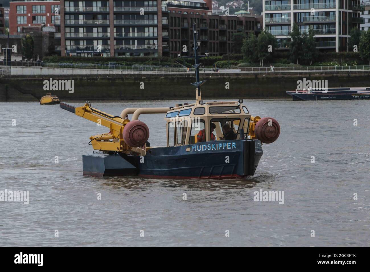 London, UK. 06 August 2021 MUDSKIPPER is a fully-mobile sculpture able to move across water and land through the use of two hydraulic step-type propulsion legs with component TREADPAD feet. British artist James Capper demonstrating how this amphibian vessel comes ashore at the Royal Docks.  A former 1980s commercial Thames workboat, MUDSKIPPER, has been transformed by James Capper into a fully mobile sculpture (9.2 metres in length and 14.5 tons in weight), which has the ability to navigate across bodies of water and land the foreshore using a set of hydraulic jacks, offering passers-by the ch Stock Photo