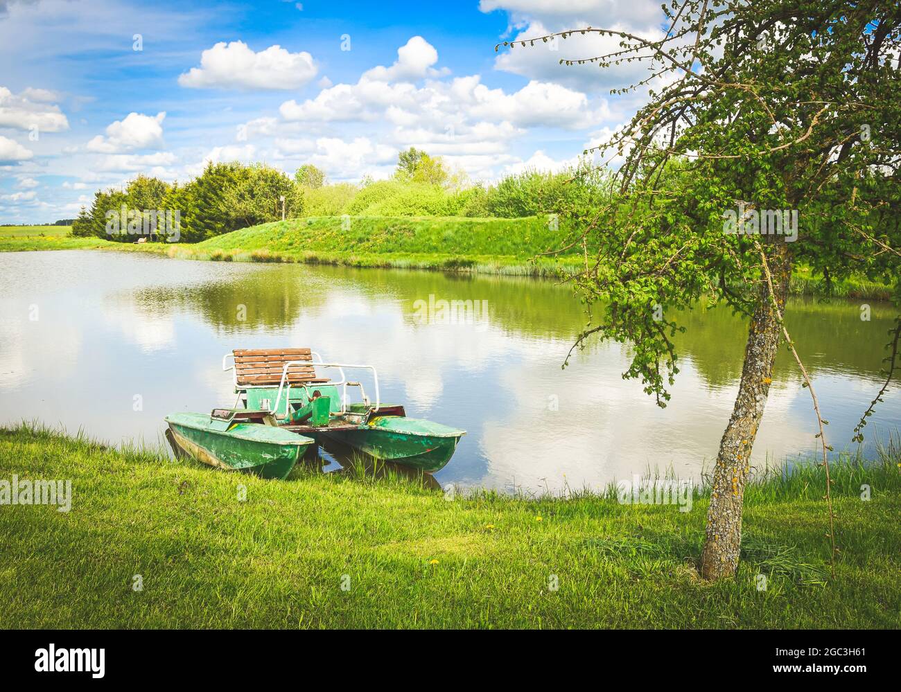 Green pedalo standing in private lake in sunny day in Lithuania countryside. Leisure activities outdoors concept. Stock Photo