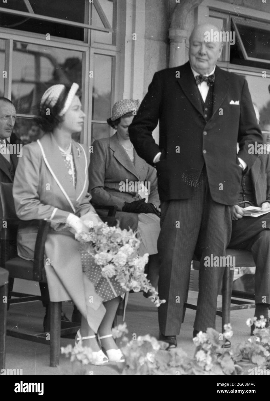 Her Royal Highness , Princess Elizabeth performs the opening ceremony of Grange Farm Centre at Chigwell , Essex , yesterday . Mr Winston Churchill was also present and made a speech . Photo shows ; Princess Elizabeth listens as Mr Churchill speaks at the opening of the Farm Centre . 12th July 1951 Stock Photo