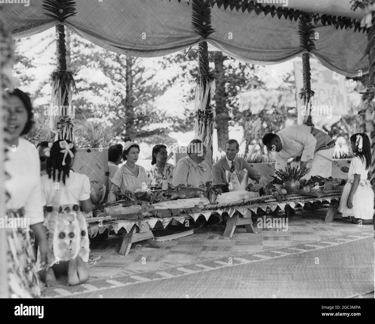Queen Elizabeth II and the Duke of Edinburgh aseated wither side of Queen Salote of Tonga during the feast on the Mala'e December 1953 Stock Photo