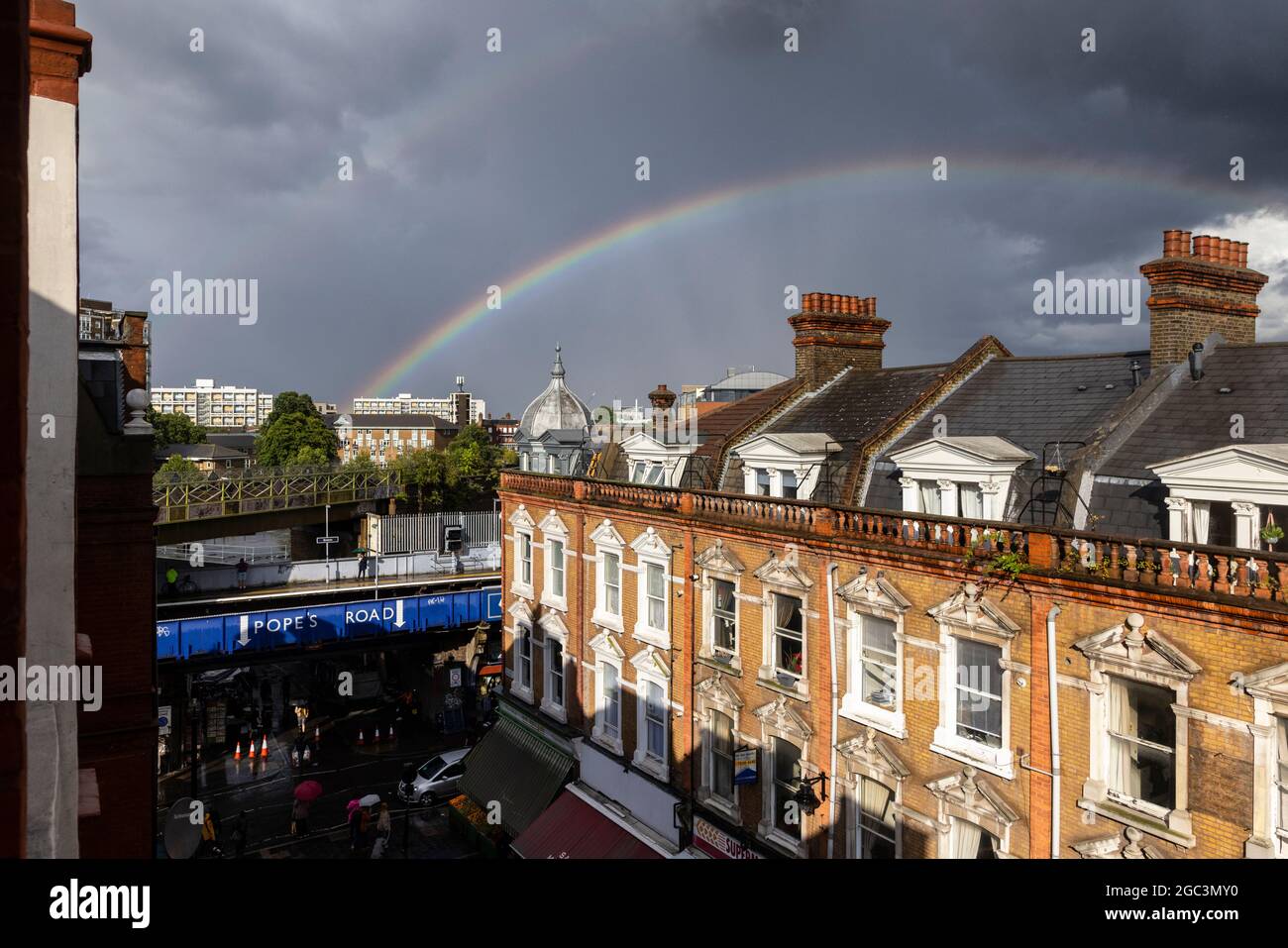 London, UK. 06th Aug, 2021. After a day of intermittent heavy rain, a rainbow is seen stretching over Electric Avenue, Brixton, London, UK. Credit: Joshua Windsor/Alamy Live News Stock Photo