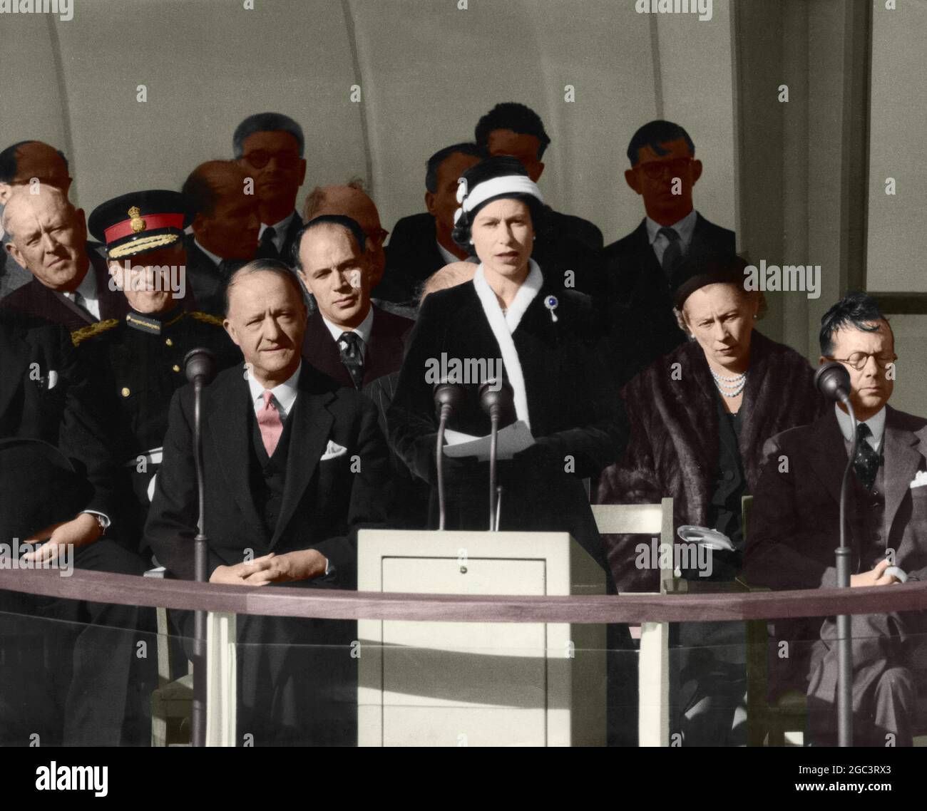 The Queen making her speech before pulling the switch which brought into operation Calder Hall, the world's first full scale atomic power station, near Sellafield, Cumberland 17 October 1956. With the Queen on the dais are Mr R. A. Butler, Lord Privy Seal (left) and Sir Edwin Plowden, Chairman of the United Kingdom Atomic Energy Authority (right). The Â£16 1/2 million plant is now switched in to the national electricity grid. Colourised photograph Stock Photo