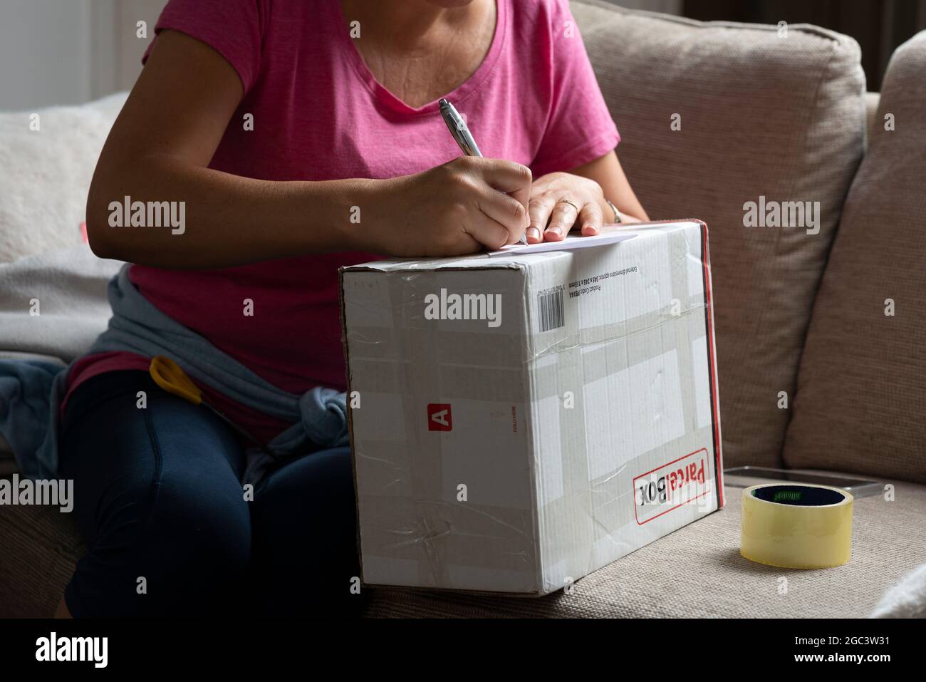 Woman writes address on  parcel , UK Stock Photo