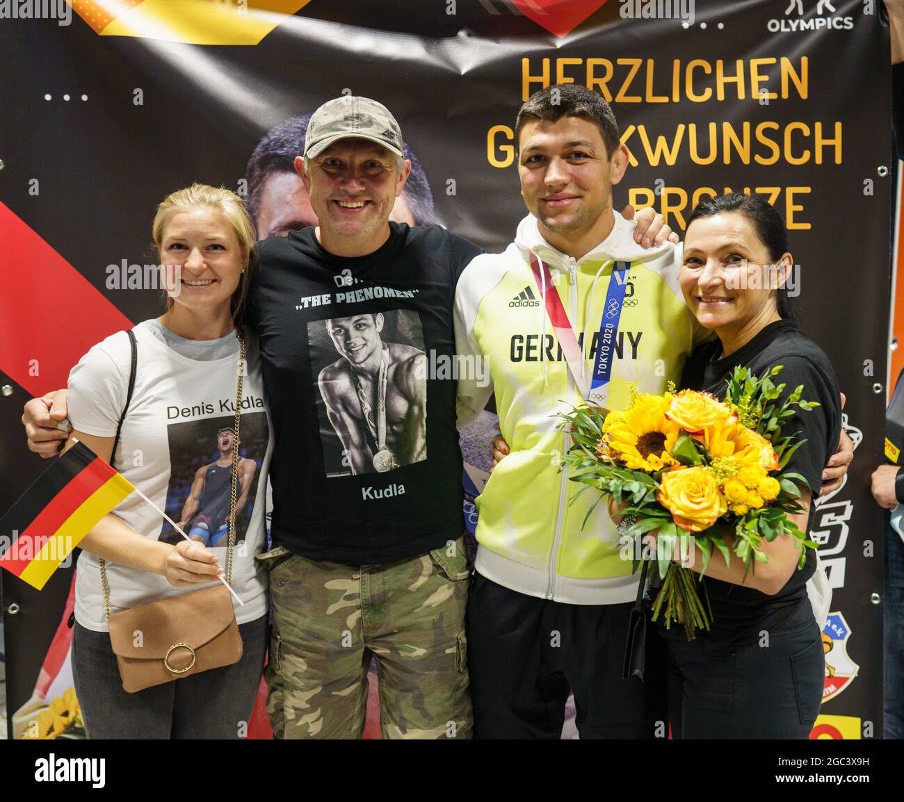 Frankfurt, Germany. 06th Aug, 2021. 06 August 2021, Hessen, Frankfurt/Main: Wrestler Denis Kudle (2nd from right) stands together with girlfriend Simone Bleng (l), father Stepi (2nd from left) and mother Karina (r) for a photo after his return from Tokyo in the evening at Frankfurt airport. He had won the bronze medal in the under 87 kg category at the Olympic Games. Photo: Frank Rumpenhorst/dpa Credit: dpa picture alliance/Alamy Live News Stock Photo