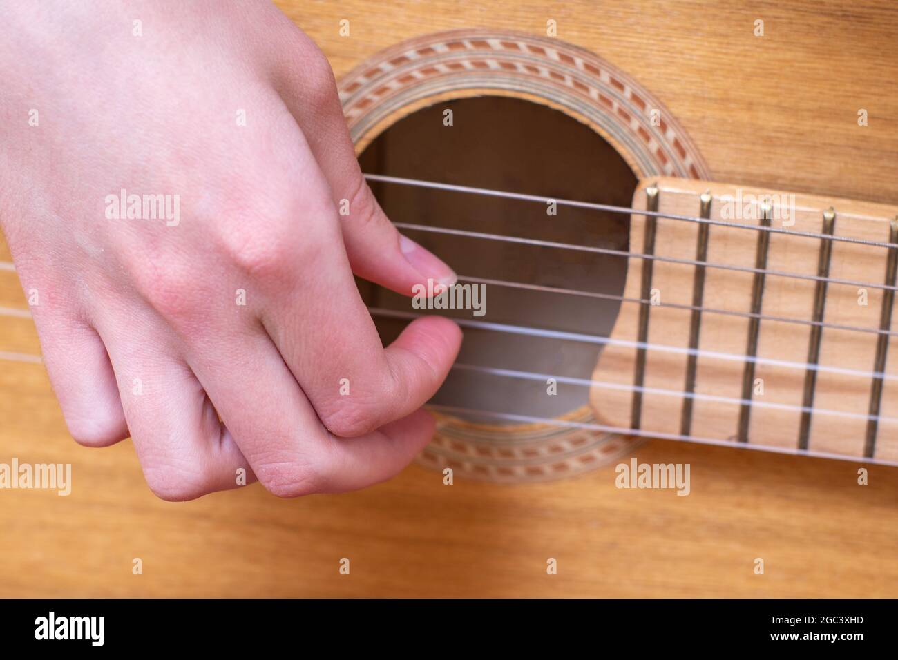 Close-up female hand picks strings of yellow acoustic guitar. Learning ...
