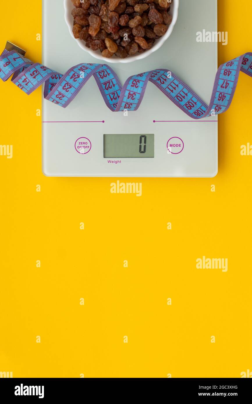 Dietary sweets without sugar, centimeter tape, scales on a yellow background. The concept of a healthy diet, weight control. Losing weight. View from Stock Photo