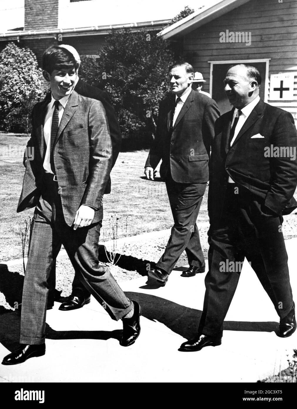 A smiling Prince Charles walks ahead of the official welcoming party at Mangalore Airport after his flight from Canberra whilst en route to Timbertop , the up-country section of Geelong Grammar School . The party is , from left : The Governor of Victoria , Sir Rohan Delacombe (obscured); Geelong Grammar Headmaster Mr TH Garnett ; and the Premier of Victoria Mr Henry Bolte . 7 February 1966 Stock Photo