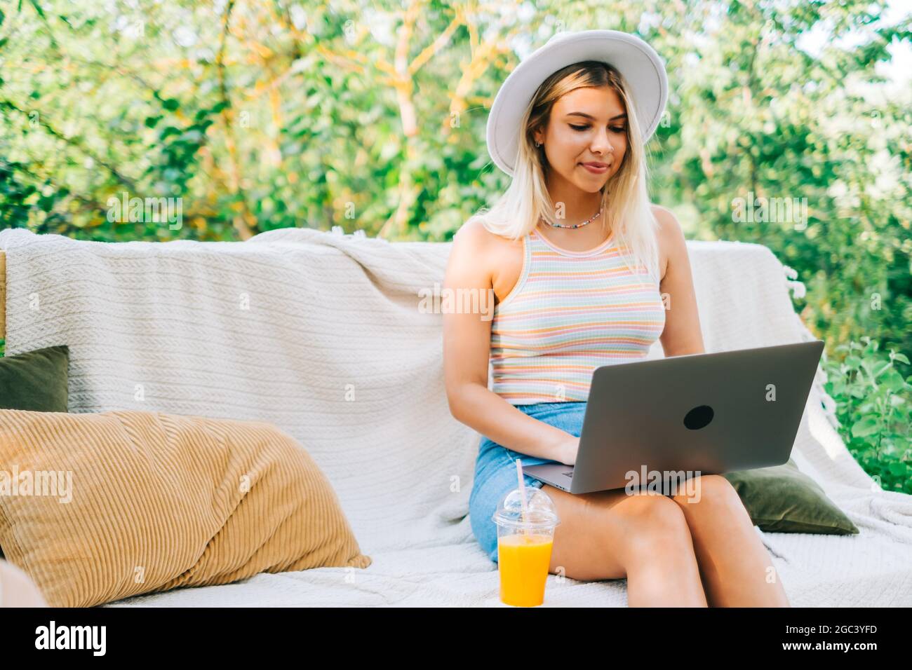 Young caucasian woman using laptop computer outdoor, sitting on a bench ...