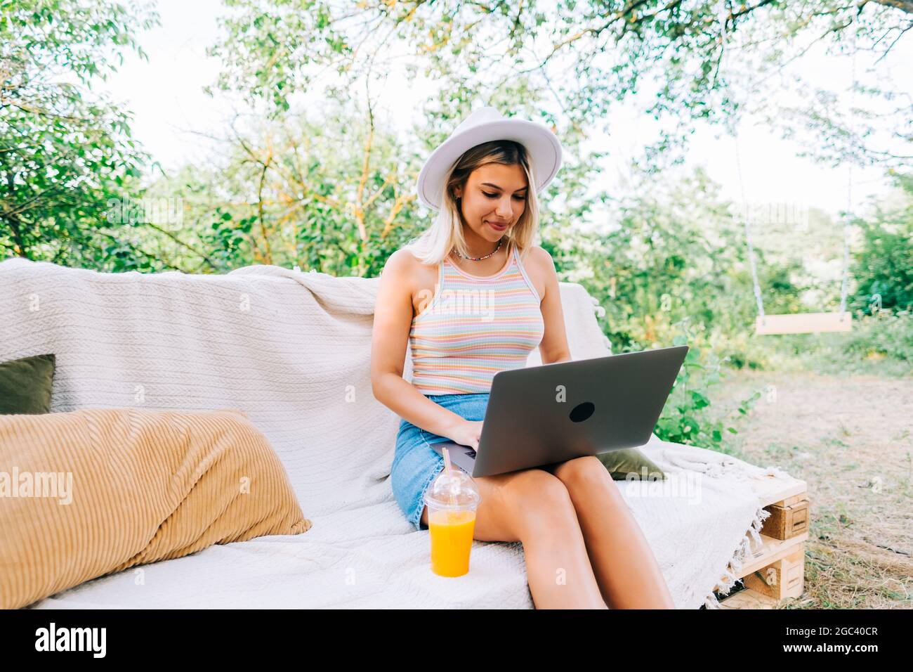 Young caucasian woman using laptop computer outdoor, sitting on a bench ...